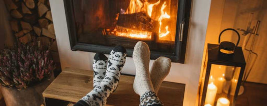 Warm room with feet in socks in front of a cozy log burner filled with kiln dried logs